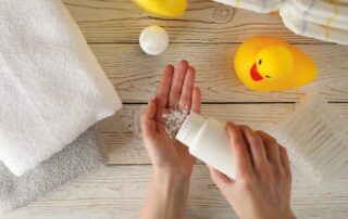 Mom applying talc powder from plastic tube. Baby hygiene