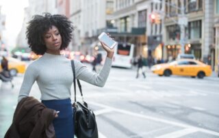 Black woman flagging down rideshare car in city