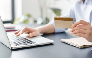 Cropped image of woman`s hands holding credit card and typing on laptop.Online shopping