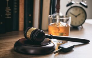Law gavel, alcohol and car keys on a wooden desk, dark background