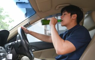 Man drinking beer while driving a car. Driving under the influence.