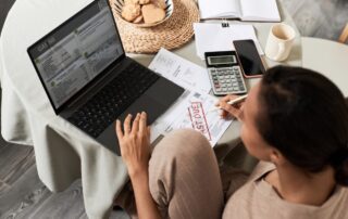 Black young woman doing taxes at home and using laptop
