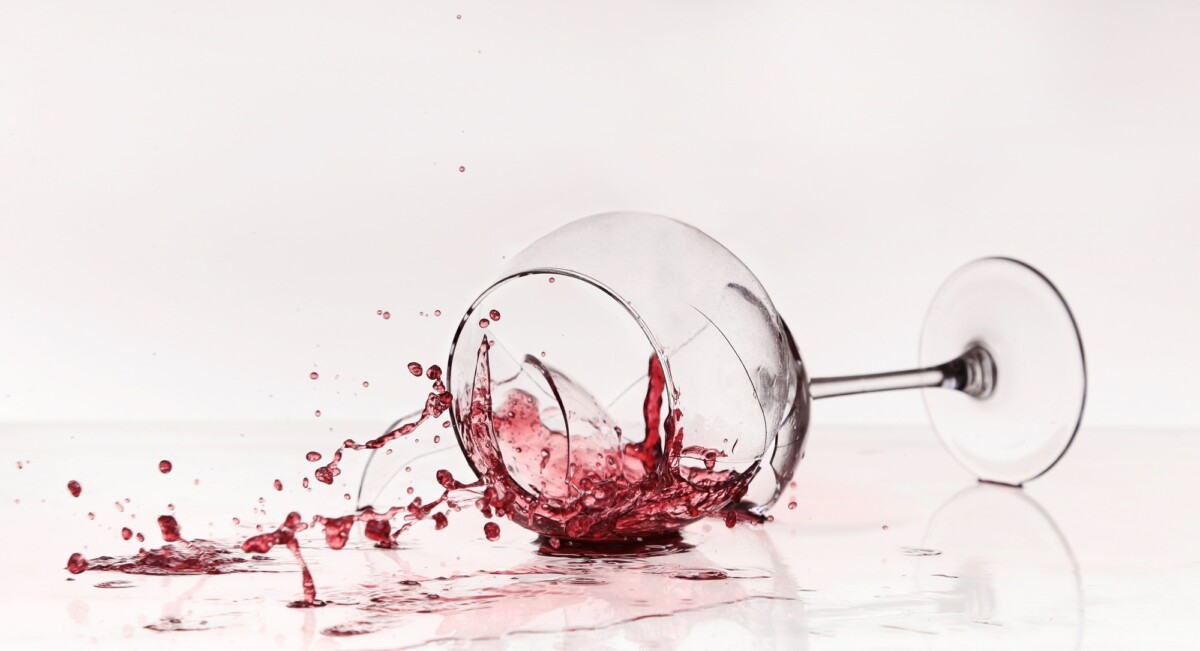 Broken wineglass on the table. Poured red wine, like blood.