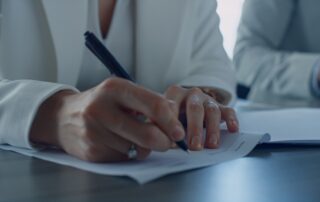 Closeup hand holding pen. Divorcing woman signing documents in attorney office.