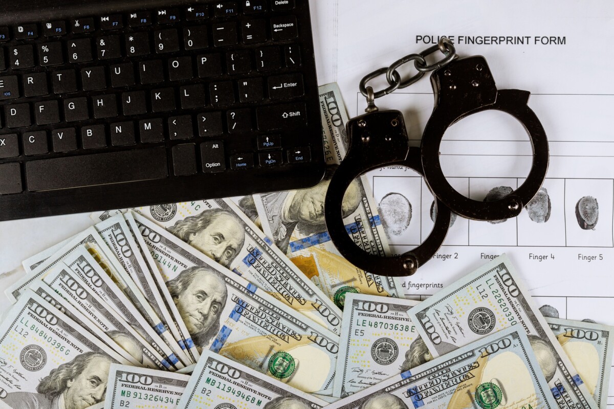 Cyber financial crime with handcuffs on money US hundred dollar bills to fingerprinting crime page
