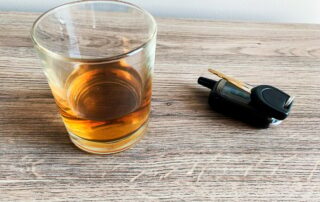 Drunk driving concept. Glass with whiskey and car key on the table.