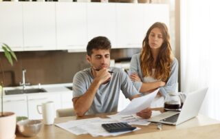 Frustrated young European couple facing financial crisis. Man with stubble sitting at kitchen table