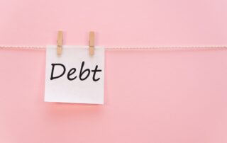 sticker with the inscription Debt hangs with a clothespin on a rope on a pink background