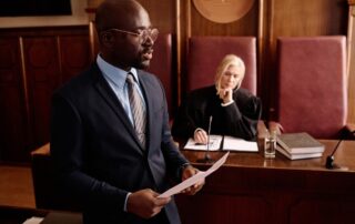 Young confident lawyer with juridical document defending suspect