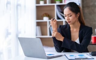 Asian businesswoman with wrist pain in the office due to working in the wrong position for a long ti
